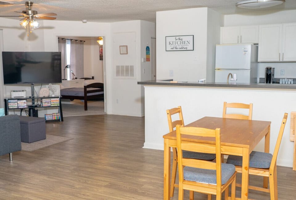 Open-concept living space with a cozy dining area, modern kitchen, and comfy lounge with a flat-screen TV.