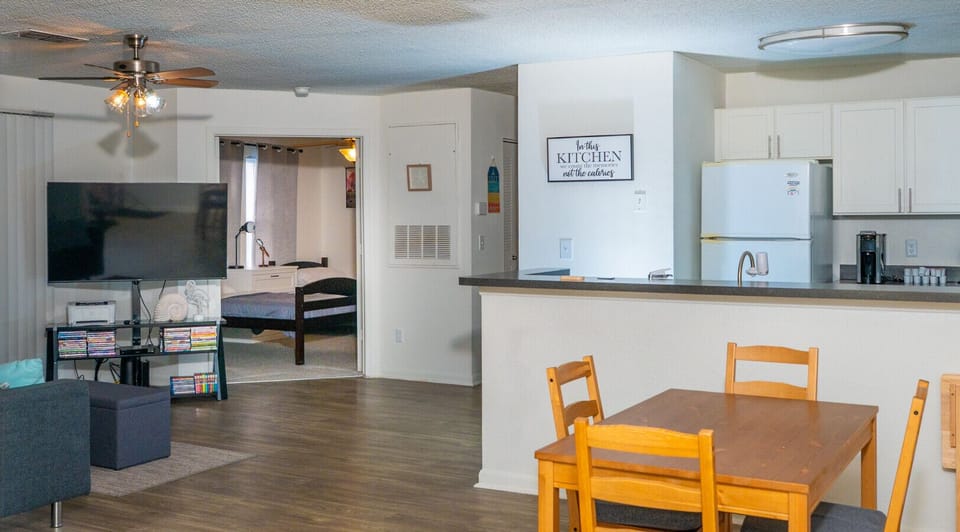 Open-concept living space with a cozy dining area, modern kitchen, and comfy lounge with a flat-screen TV.