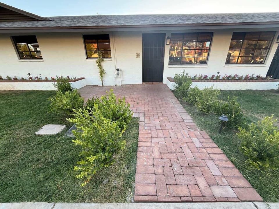 Welcoming front entrance with a private door, flower-filled planter boxes, and a brick path framed by fresh landscaping—offering charm and curb appeal from the start.