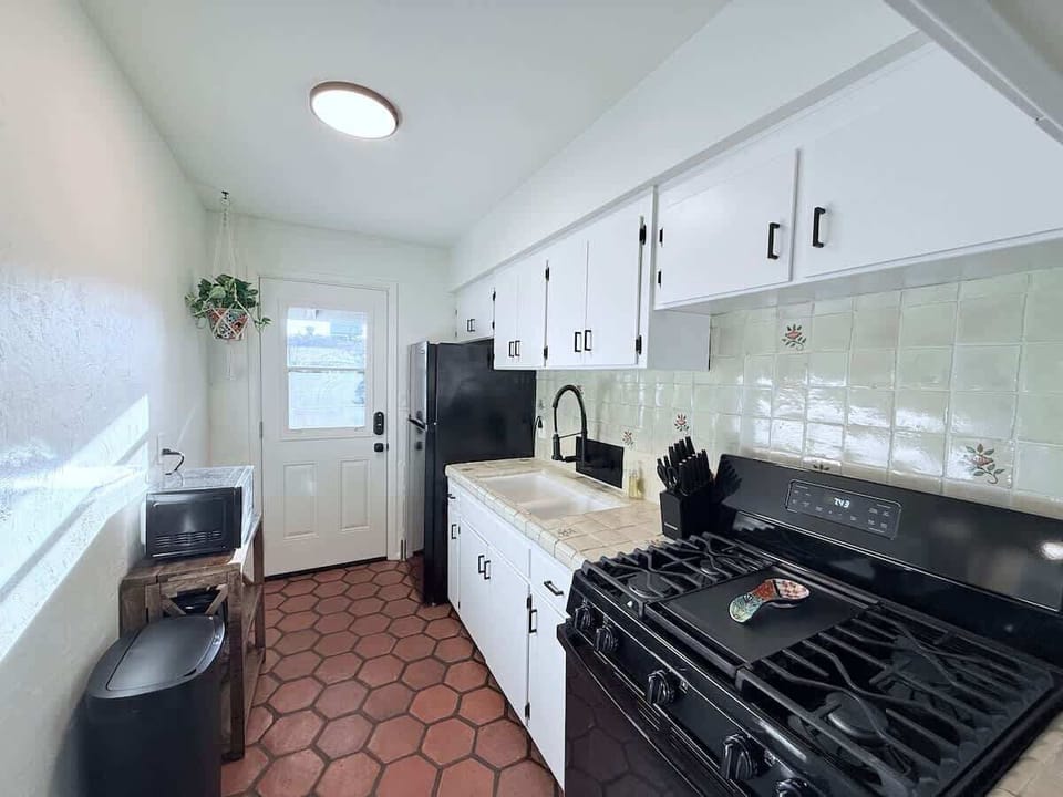Bright and functional kitchen with vintage tile countertops,  new appliances, and a back door that leads directly to backyard retreat.