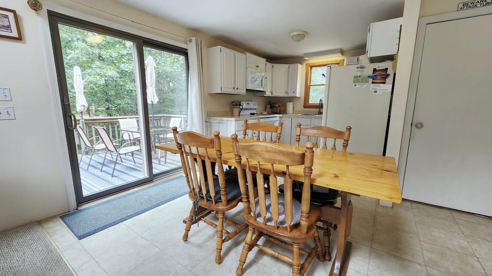 Dining area with slider to deck and kitchen beyond