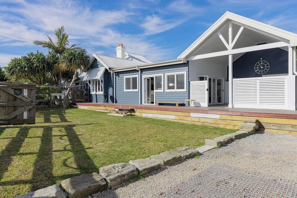 The fully fenced backyard provides a generous space to relax or play, with lush grass, a peaceful coastal vibe, and direct access from the deck.