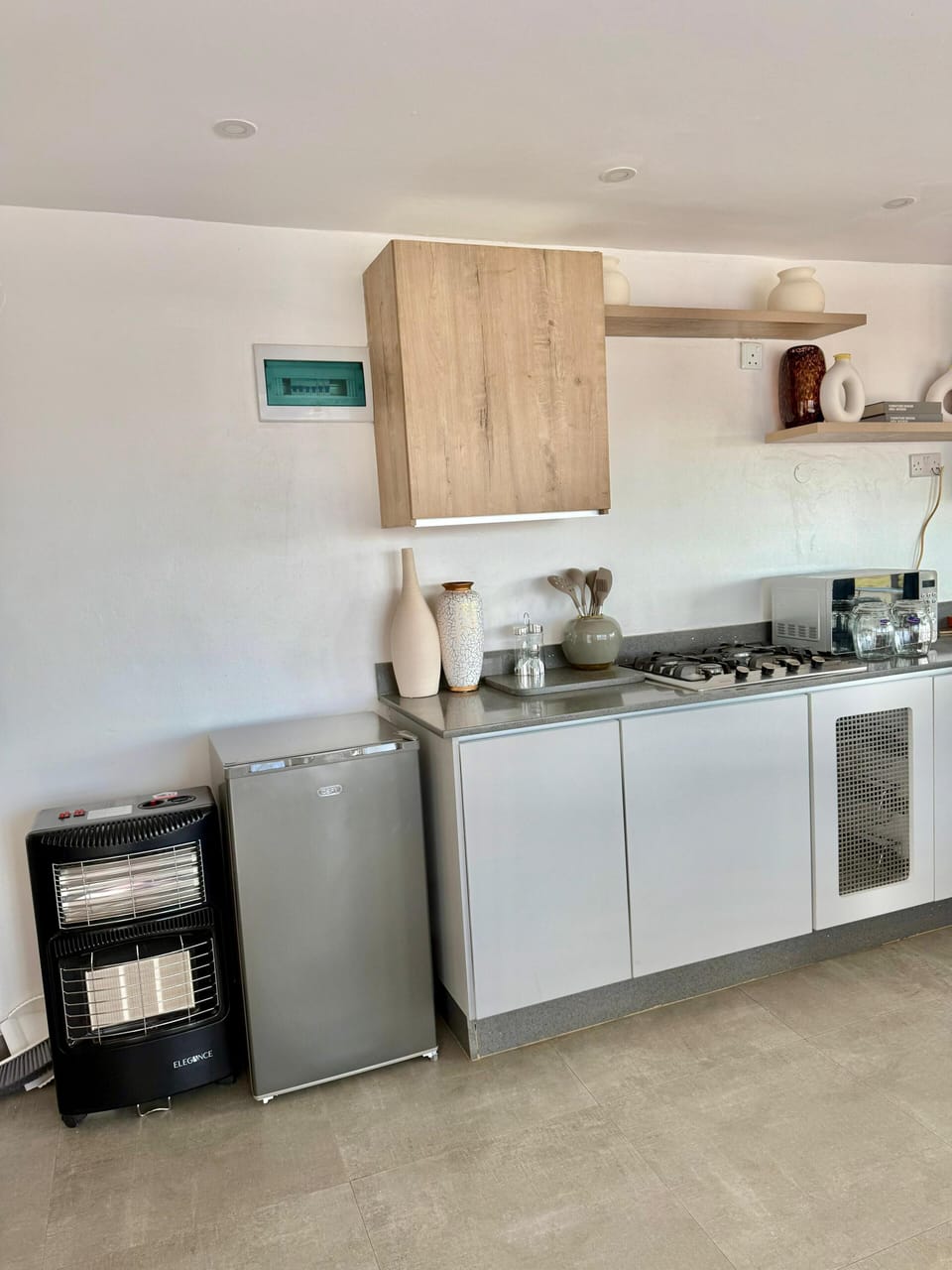 Fully equipped kitchen with gas hob, refrigerator, heater, microwave and kettle.