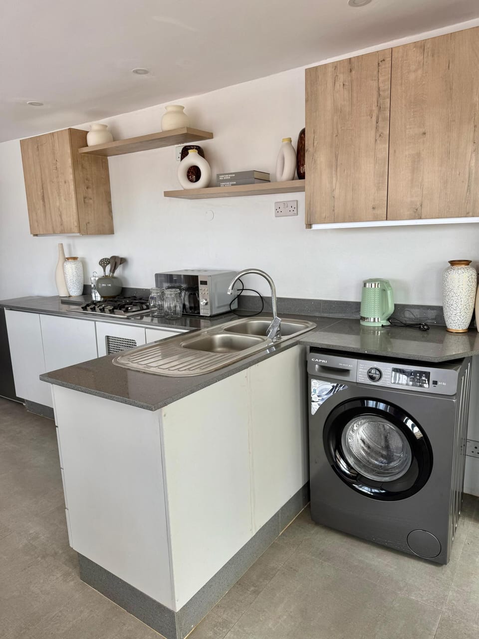 Fully equipped kitchen with gas hob, microwave, washer and kettle.