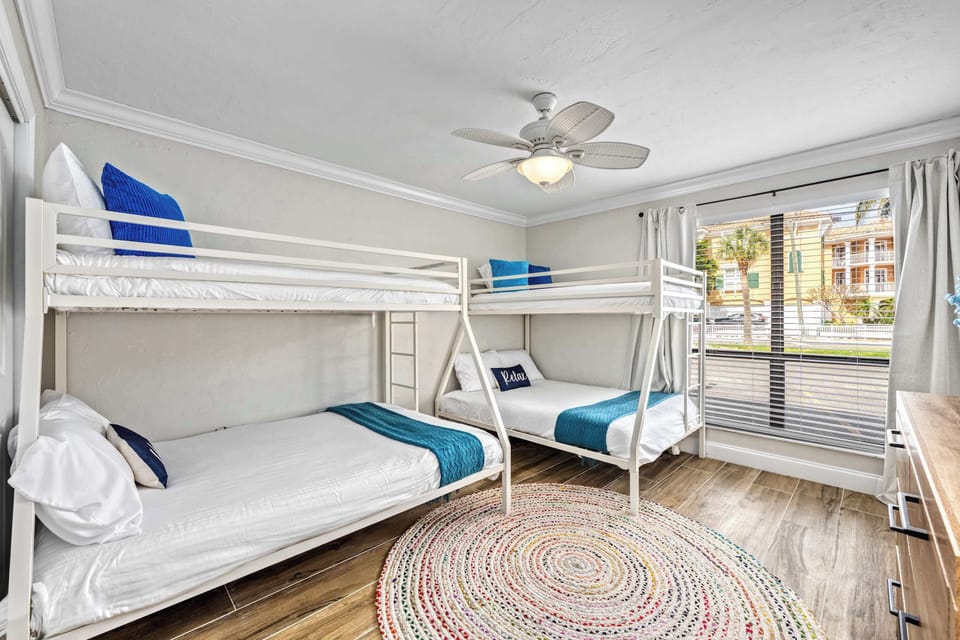 Family-friendly guest bedroom with two queen beds, matching twin bunks, and a Smart TV – sleep under the island breeze in comfort.