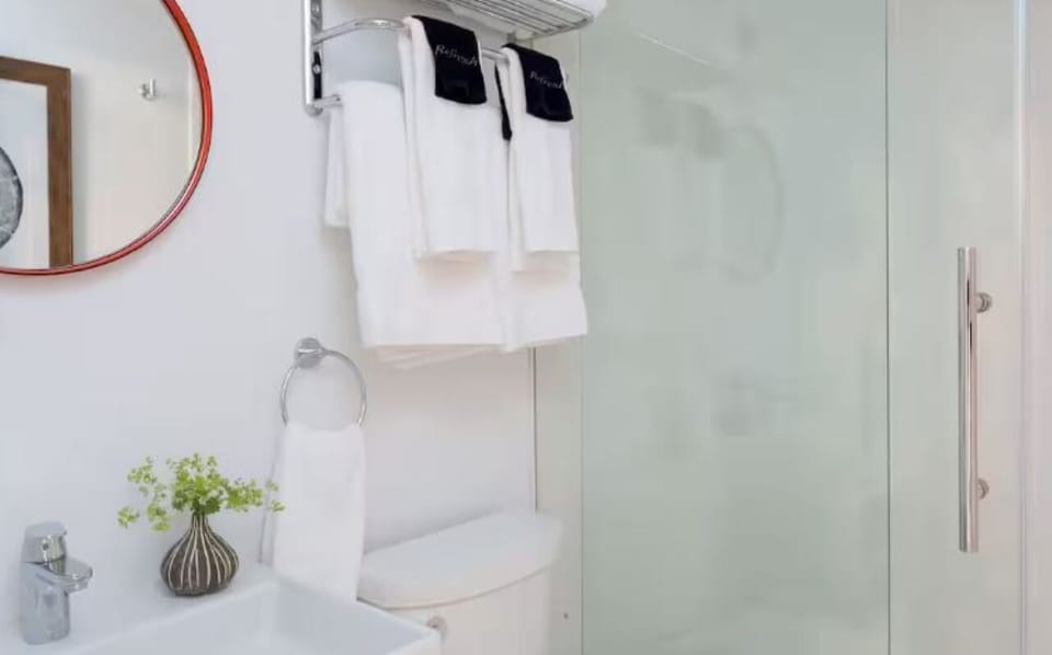 Refresh under a sleek glass shower with fluffy towels ready.