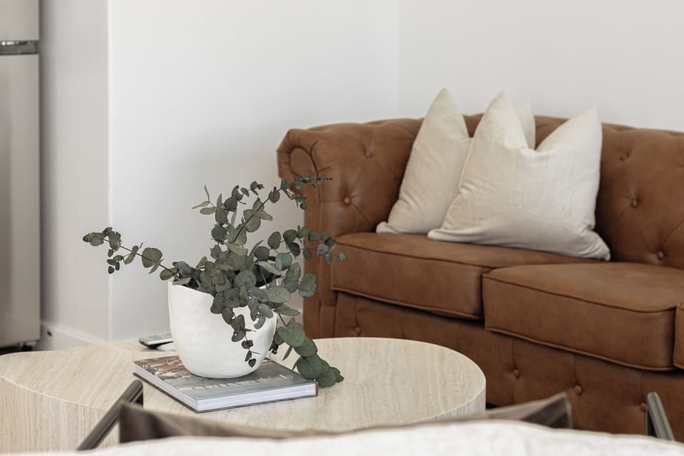 Relax on a comfortable leather sofa with soft pillows. A stylish coffee table with modern decor creates a cozy atmosphere.