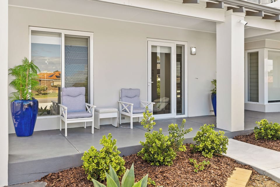 Relax and enjoy the fresh air on our charming covered patio. This inviting outdoor space features comfortable armchairs with striped cushions and a small side table, perfect for enjoying a morning coffee or an evening chat.