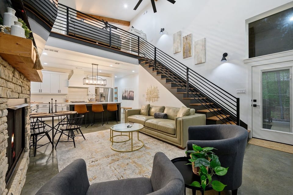 The warm living room features soaring ceilings, wood beams, and a stunning stone fireplace perfect for relaxing evenings.