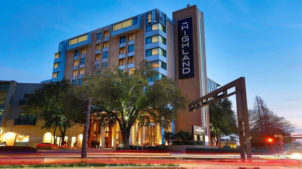Arrive to a dramatic, city-lit hotel entrance at dusk.