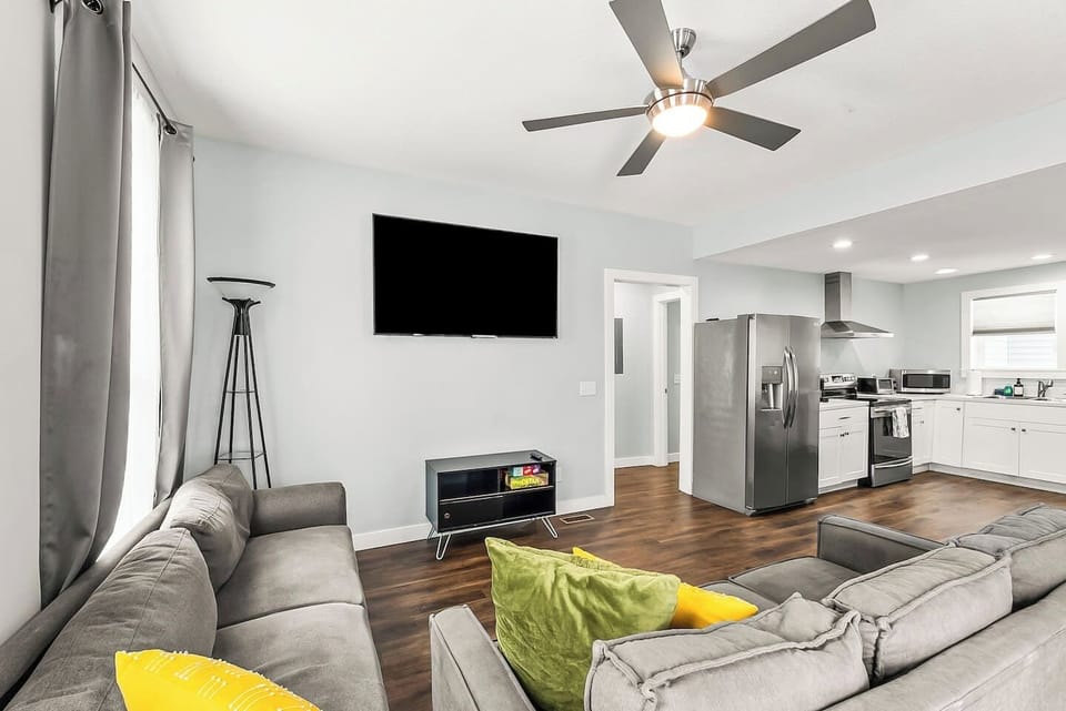 Comfort meets convenience in this inviting living room with a large TV, board games, and easy access to the kitchen and dining area.