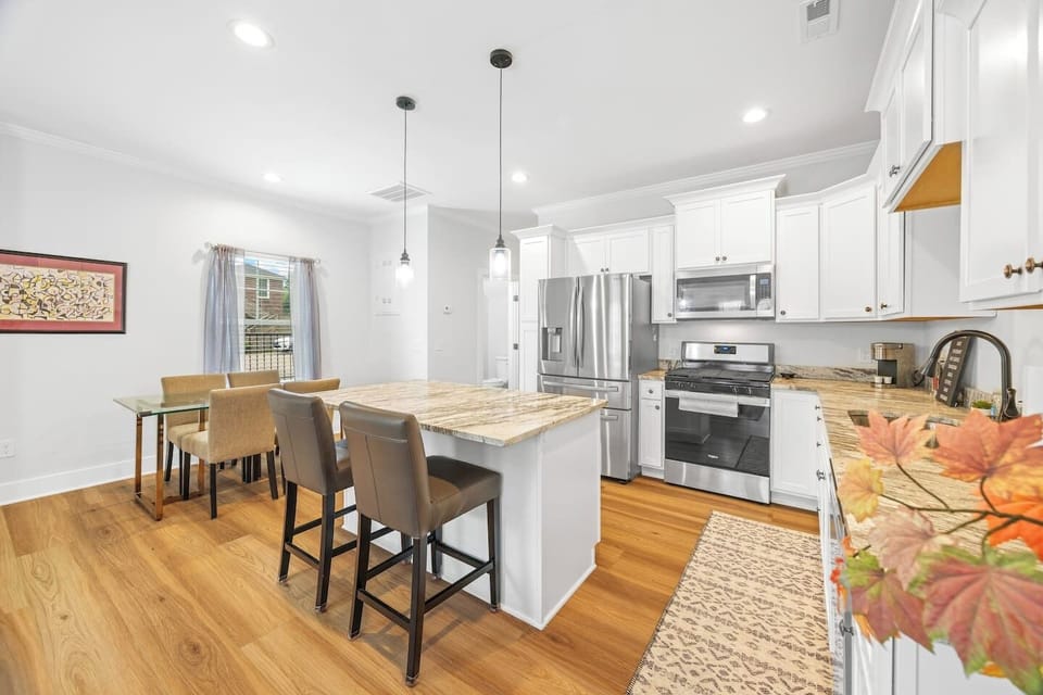 Gather for meals or morning coffee in this cozy dining area featuring a glass-top table, four cushioned chairs, and a large window that fills the space with sunlight.