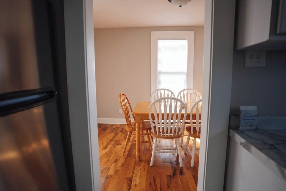 The dining area has a solid wooden table with six chairs, great for meals or hanging out. 