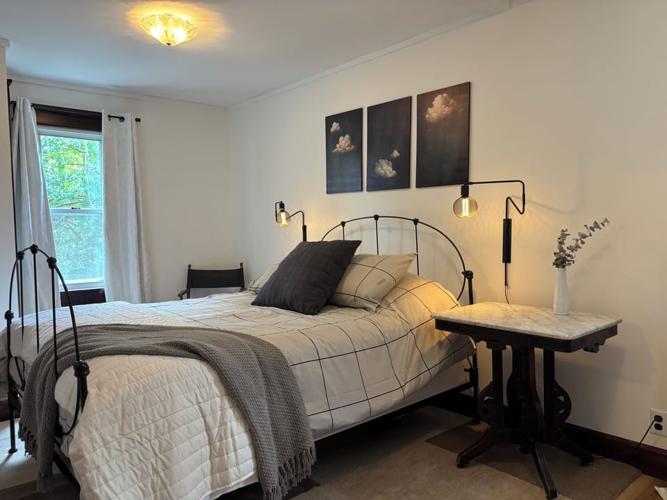 Comfortable queen bed with natural lighting and soft linens