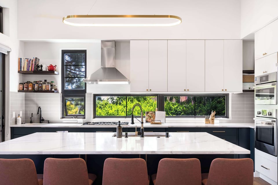 Bar stools add warmth to the marble island, with open shelves showcasing cseasoning jars beside the range.