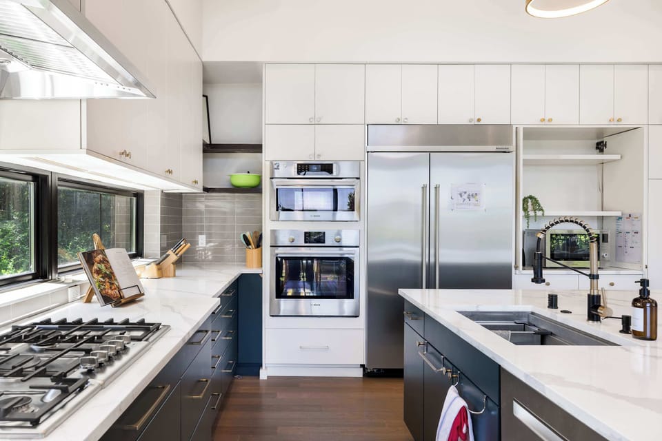 Spotless white cabinets with stainless appliances, where the red-striped dish towel adds a playful pop against dark lower cabinets.