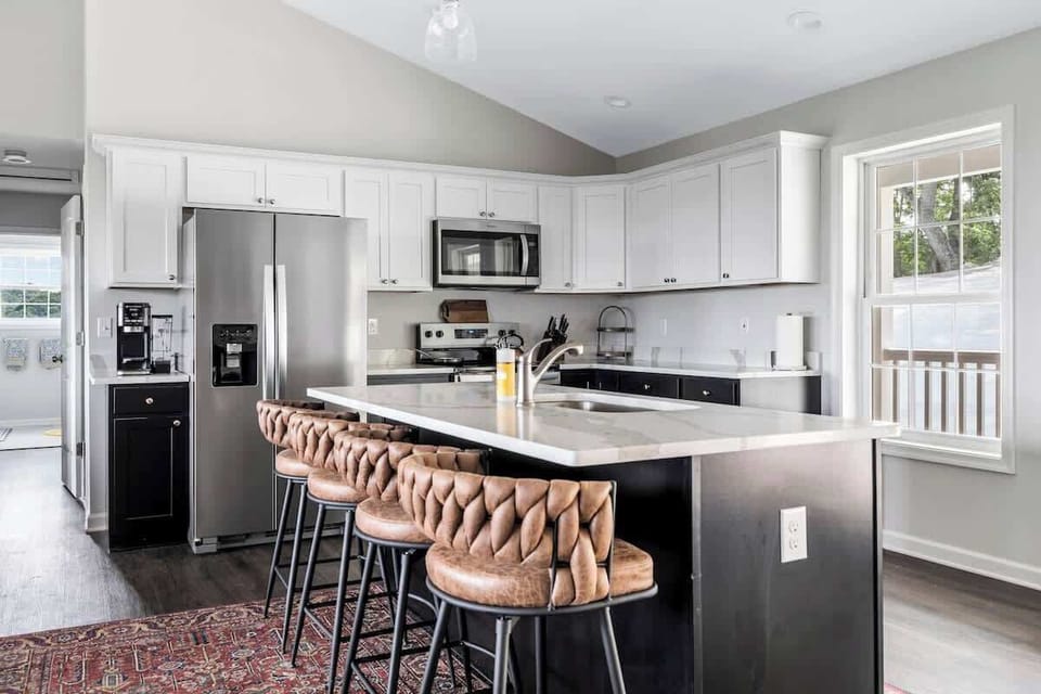 Modern kitchen with island, leather barstools, and stainless appliances