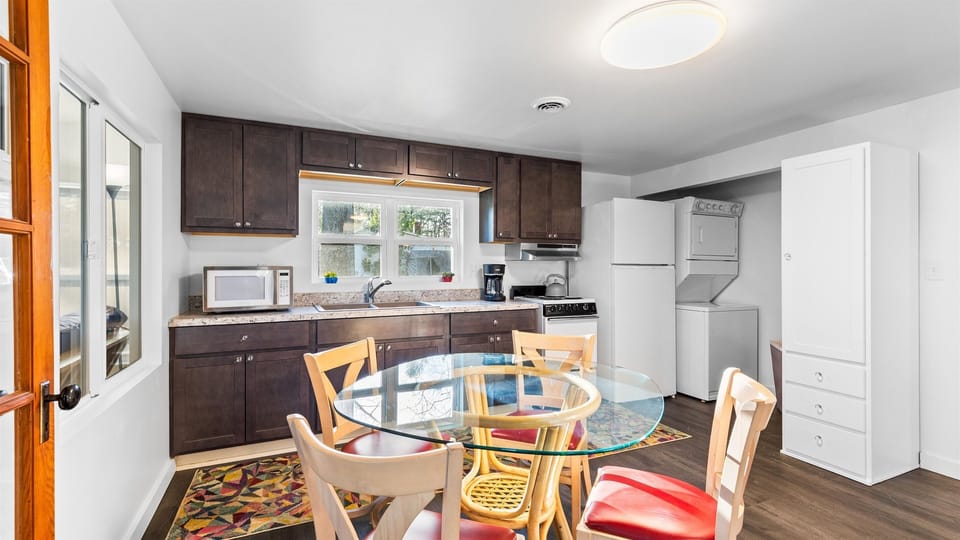 Fully stocked kitchen with seating for 4, electric stove, coffee brew pot, microwave and fridge