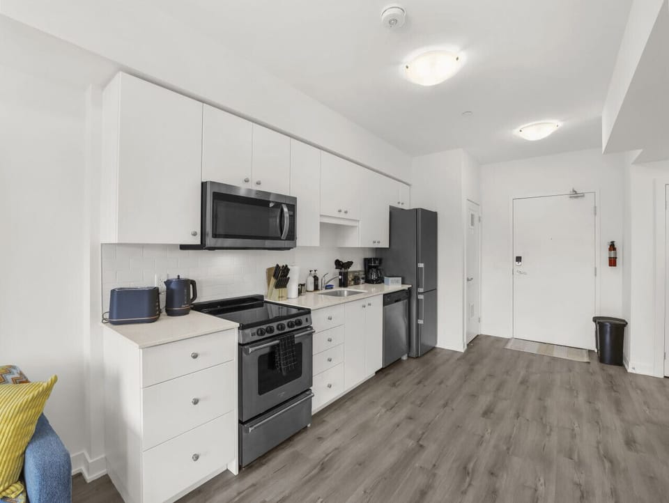 Whip up a meal in this pristine kitchen. Featuring sleek white cabinets, stainless steel appliances, and all the essentials for cooking. Everything you need for a comfortable stay is right here.