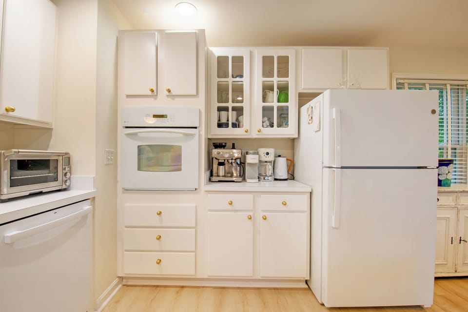 610 Castle Ct - Functional Kitchen and Pantry Storage - The kitchen is designed for efficiency with ample counter space, a built-in microwave, and classic white appliances. Glass-front upper cabinets and plenty of drawer storage provide both style and utility for vacation or year-round living.