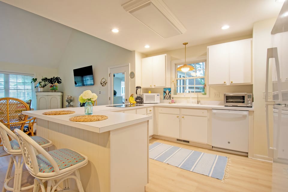 610 Castle Ct - Bright Gourmet Kitchen with Island - The updated kitchen features crisp white cabinetry, a center island with casual seating, and updated pendant lighting. The open layout ensures the chef remains part of the conversation while overlooking the vaulted living area.