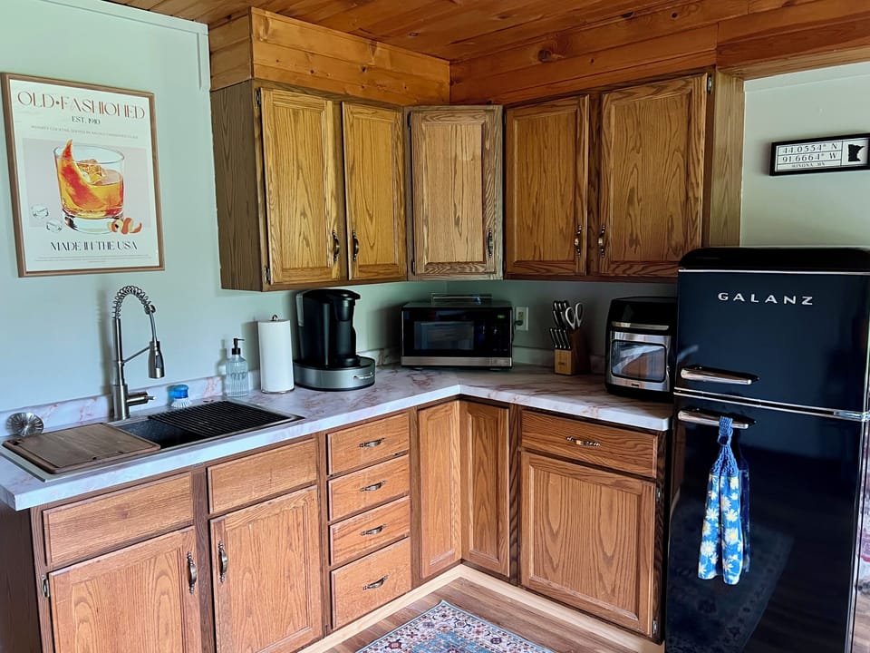 Kitchen with fridge, coffee maker & coffee, microwave, air fryer.