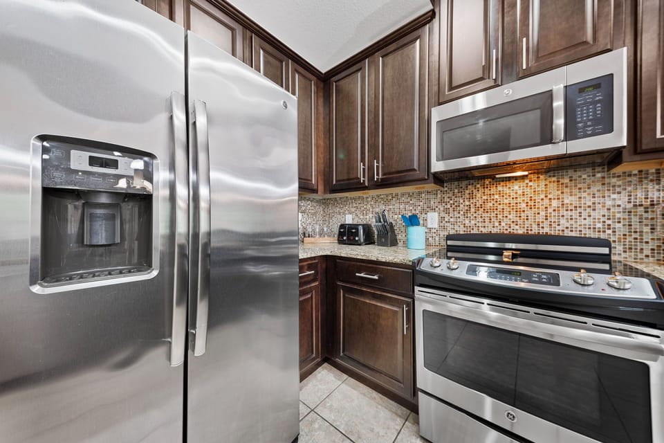 Modern kitchen with stainless appliances, granite counters, coffee maker, cookware, and breakfast bar for casual dining.