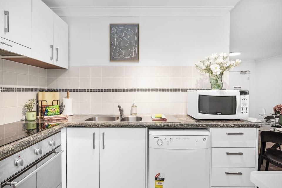 Discover our modern kitchen, featuring sleek white cabinetry, a durable granite countertop, and essential appliances.