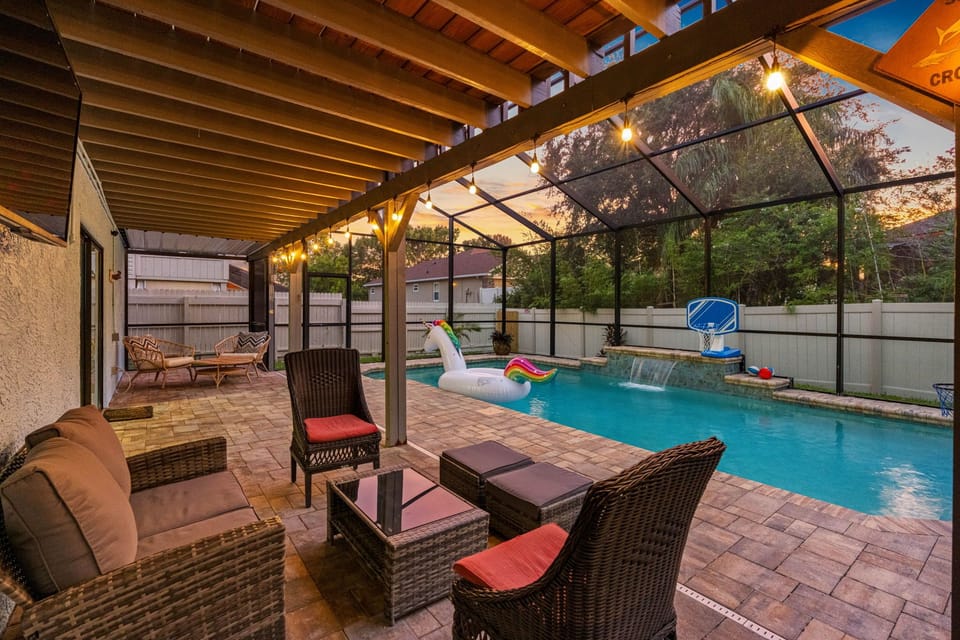 Enjoy resort vibes with this spacious screened-in pool area—complete with wicker lounge seating, a shaded patio, and fun inflatables for the whole family.