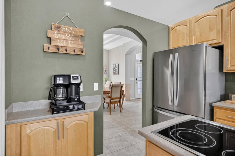 Modern kitchen area featuring an induction stovetop, refrigerator, and a coffee station for your convenience.