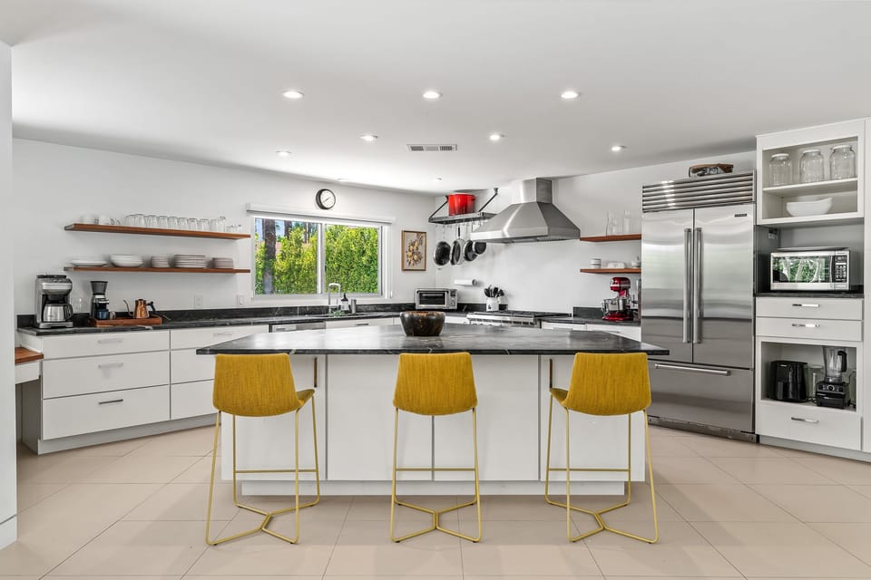 Fully stocked chef’s kitchen with Wolf gas stove, Subzero fridge, Fellow coffee maker, and oversized soapstone island