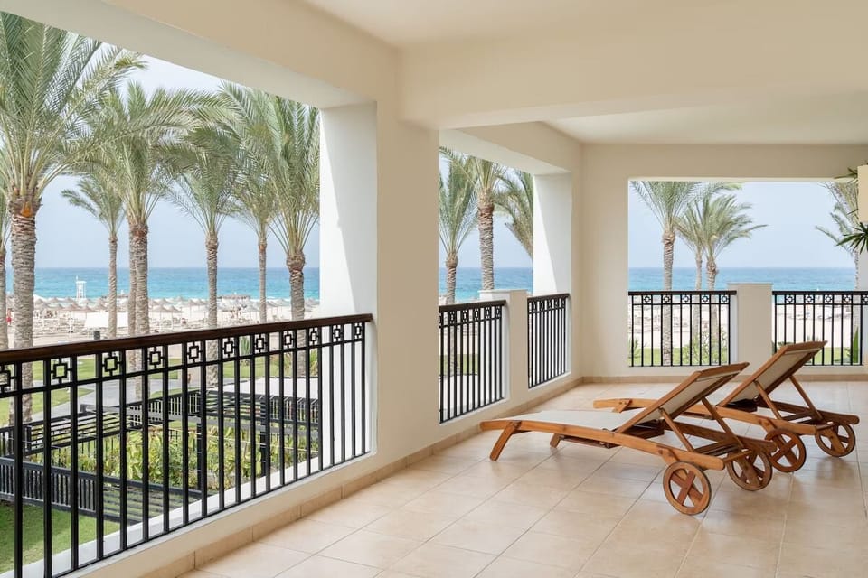 Unwind on sun loungers while waves shimmer beyond palms