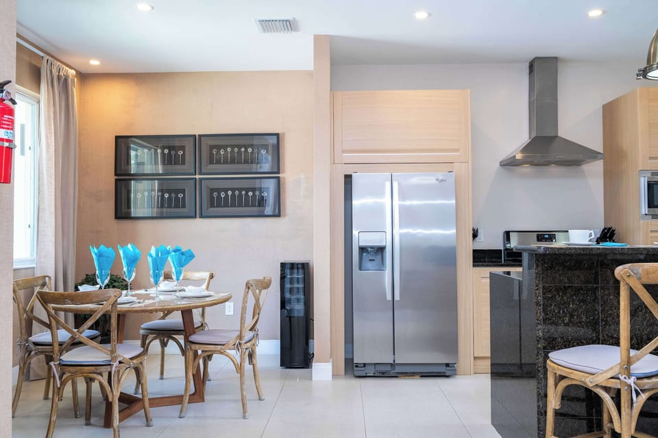 Gather for meals in this cozy dining nook with rustic chairs and chic table settings, surrounded by modern kitchen amenities and stylish wall art.