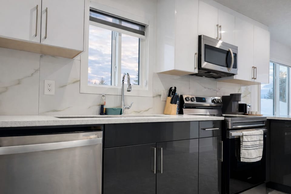 Complete kitchen setup with stainless steel oven, fridge, and dishwasher.