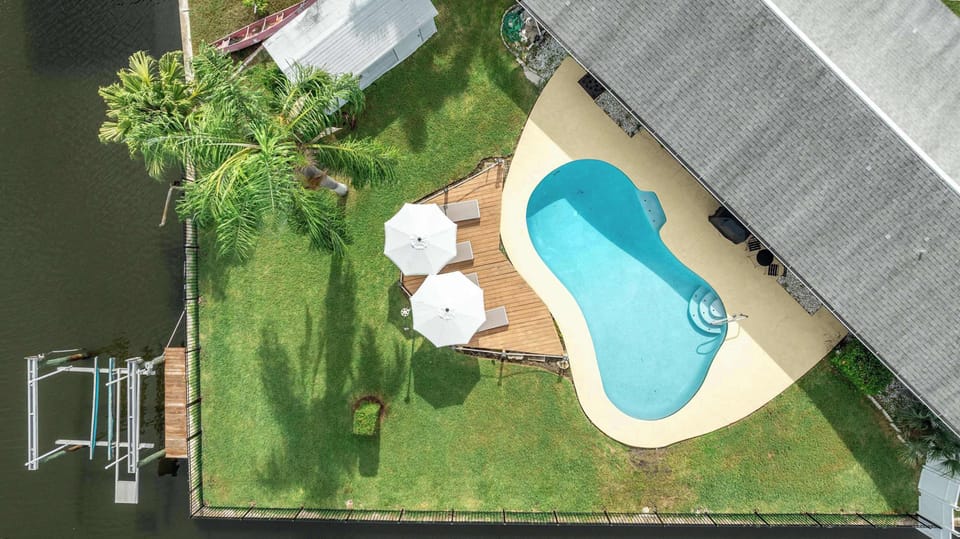 Sparkling pool, sunny deck with umbrellas, lush lawn, and private canal access. Perfect for lounging, swimming, and launching your next boating or fishing adventure right from your backyard.