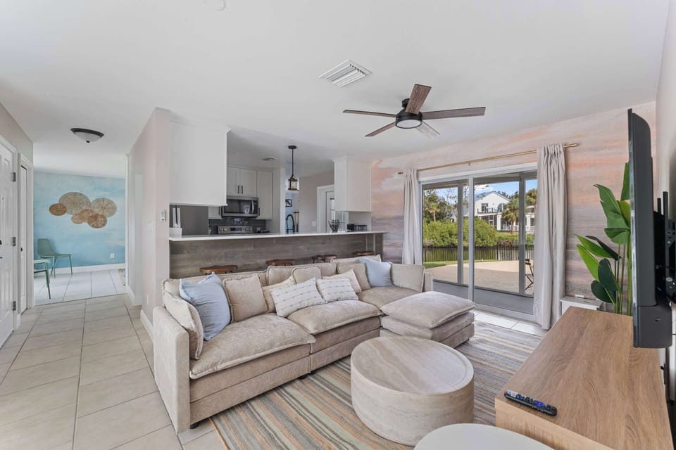 Spacious living room with large windows, natural light, and coastal décor offers the perfect spot to gather, relax, and recharge.