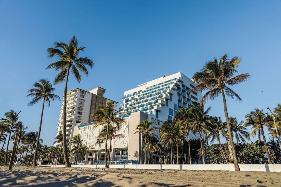 Step from the lobby toward palms and sandy beachfront.