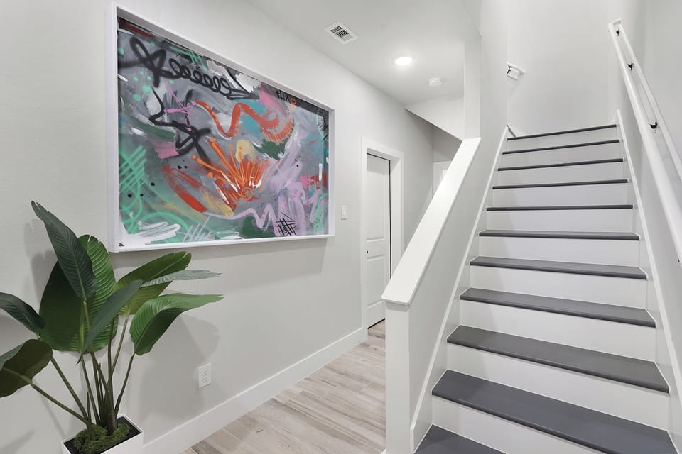 Striking abstract art and a modern staircase define this stylish entry.