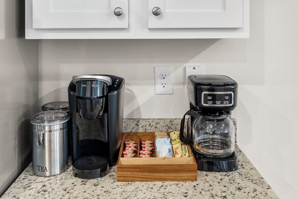Start your morning right with your personal coffee station featuring both Keurig and drip coffee makers, plus tea and sweeteners.