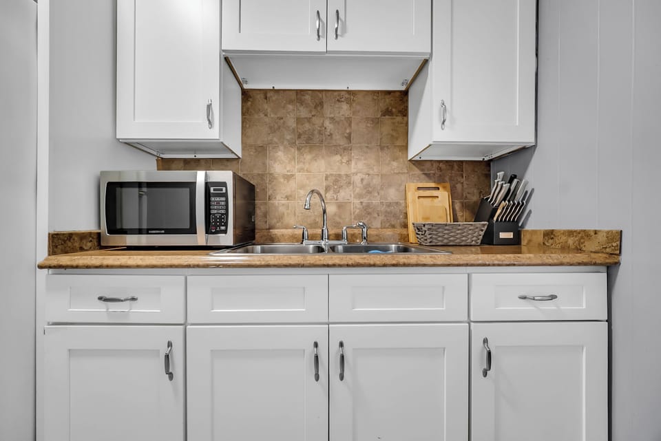 Functional Kitchen setup with Full sink, microwave and cooking utensils.