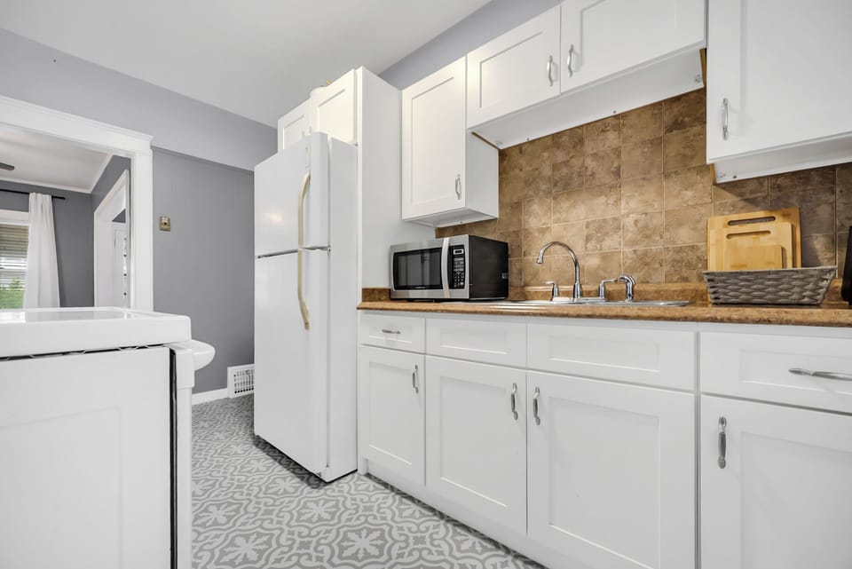 Fully stocked kitchen with crisp white cabinetry, microwave & full-size fridge