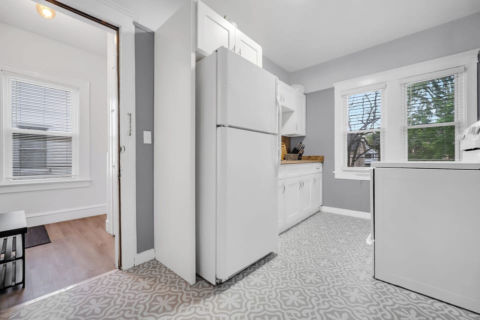 Bright, fully equipped kitchen featuring white cabinetry and full-size fridge