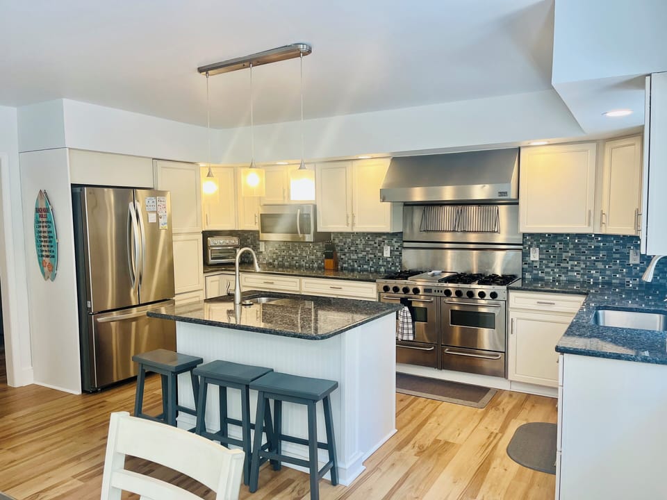 Kitchen has two sinks, island seating for three