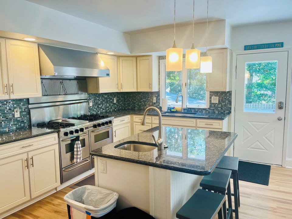 Kitchen has two sinks, island seating for three