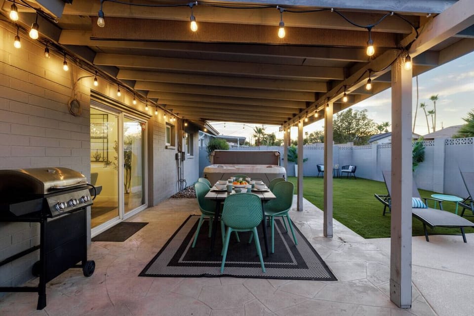 Covered patio dining area with BBQ grill and hot tub nearby