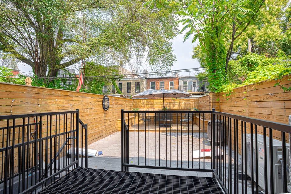 Serene private backyard patio with comfortable seating, string lights and lush greenery