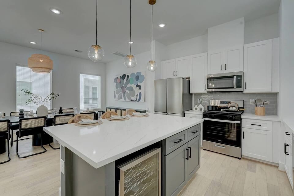 Modern kitchen with large island, pendant lights, and stainless appliances.