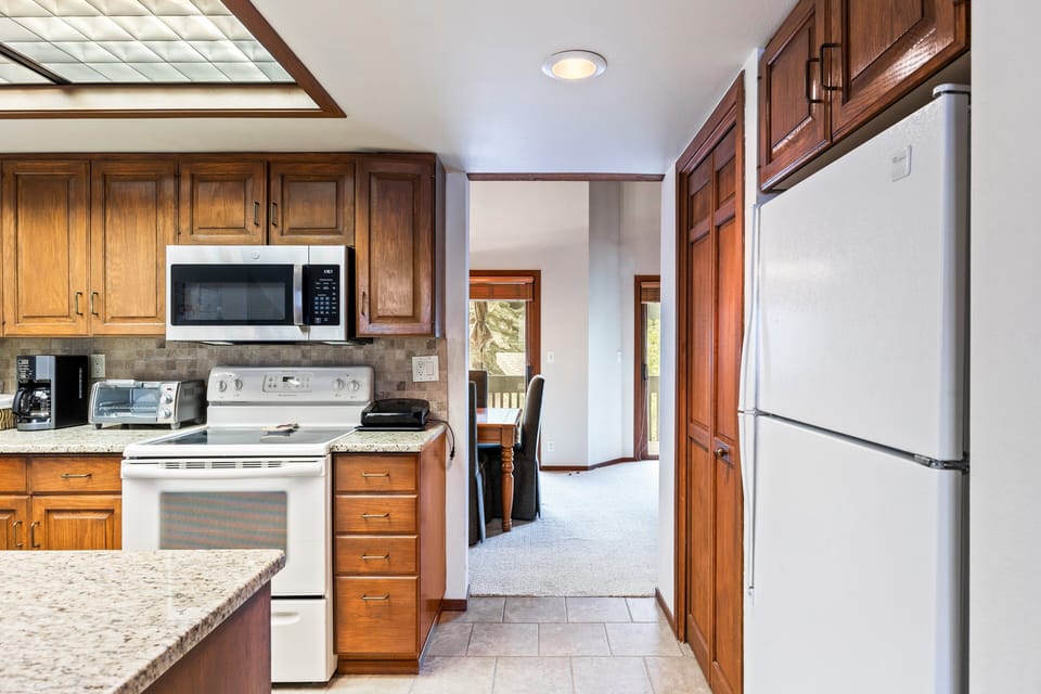 - Kitchen with granite counters and modern appliances  
- Wooden cabinetry and white fridge for a classic mountain touch  
- Open design flows into dining area with natural light