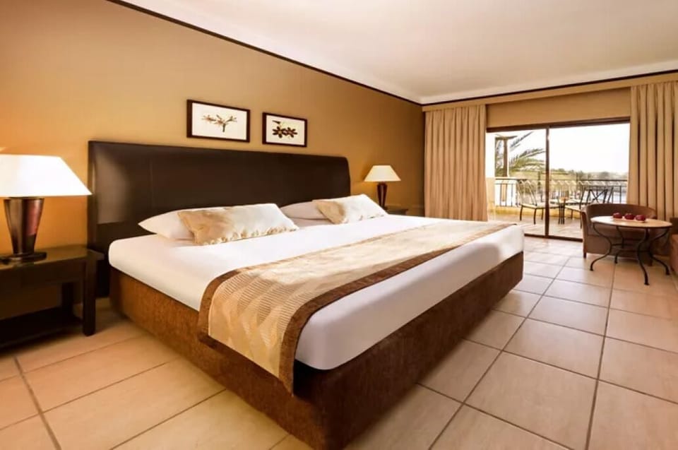 Unwind into a crisp king bed beside sunny balcony doors.