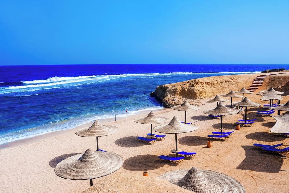Lounge beneath thatched umbrellas while waves roll in softly.